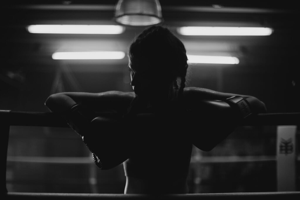 une femme prend appuie sur les cordes d'un ring de boxe 