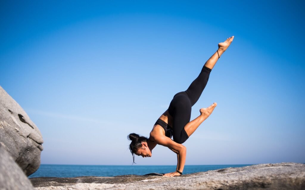 Vue en contre-plongée d'une femme faisant du yoga sur la plage dans un ciel bleu